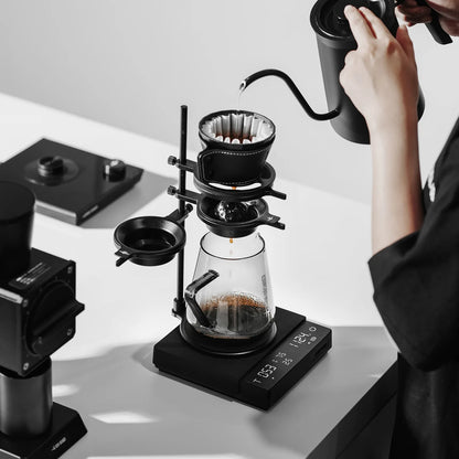 Pour-over coffee being made with black MHW-3BOMBER Cube Coffee Scale 3.0 Pro Max, kettle, and brewing setup.