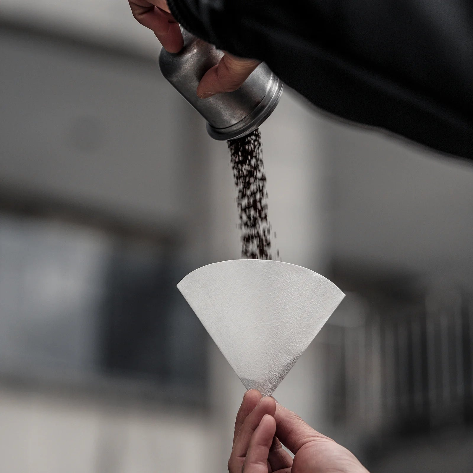 MHW-3BOMBER cone coffee paper filter, white, single-use, for 1-4 cup drippers. Coffee grounds being poured into filter.