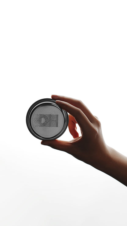 MHW-3BOMBER DH Filter Basket 58mm for espresso, held in hand. Silver tone with patterned holes. 