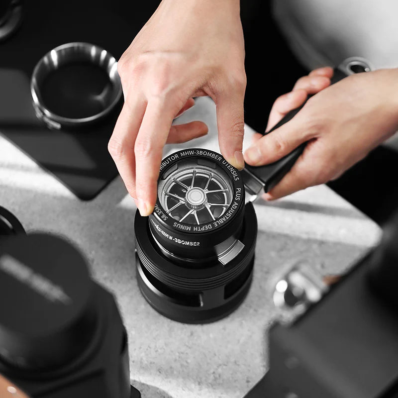 MHW-3BOMBER YU Series coffee distributor being adjusted. Black aluminum alloy, glass top. 