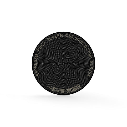 A close-up of the MHW-3BOMBER Espresso Puck Screen Titanium Plated Black shows its double-layer design with perforated holes. Text on the edge reads ESPRESSO PUCK SCREEN Φ58.5mm 0.2mm THIN BOOMER. The titanium-coated screen is set against a white background.