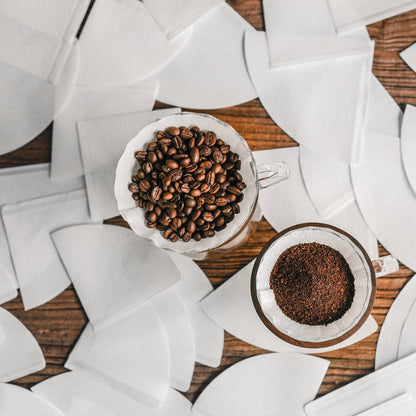 MHW-3BOMBER coffee filters. White cone paper filters in glass with beans and grounds. 