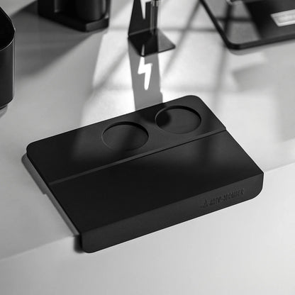 MHW-3BOMBER black silicone tamper mat with two holes for espresso portafilter. Protects counters during tamping.