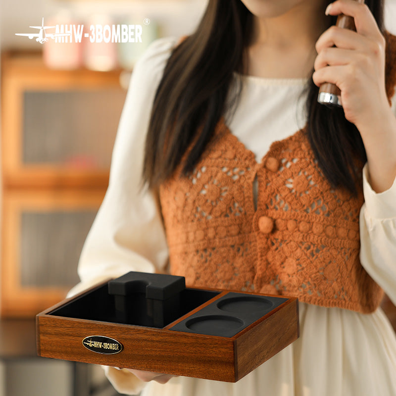 MHW-3BOMBER espresso tamping station. Wood, black silicone mat. Holds portafilter and tamper. Compact design for home coffee setup.