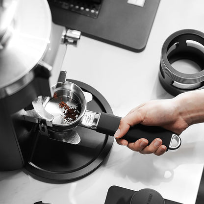 Person using a manual coffee grinder with a focus on the coffee beans.