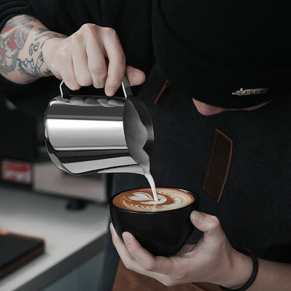 MHW-3BOMBER GT Milk Pitcher being used to pour latte art. Stainless steel with u-shaped spout.