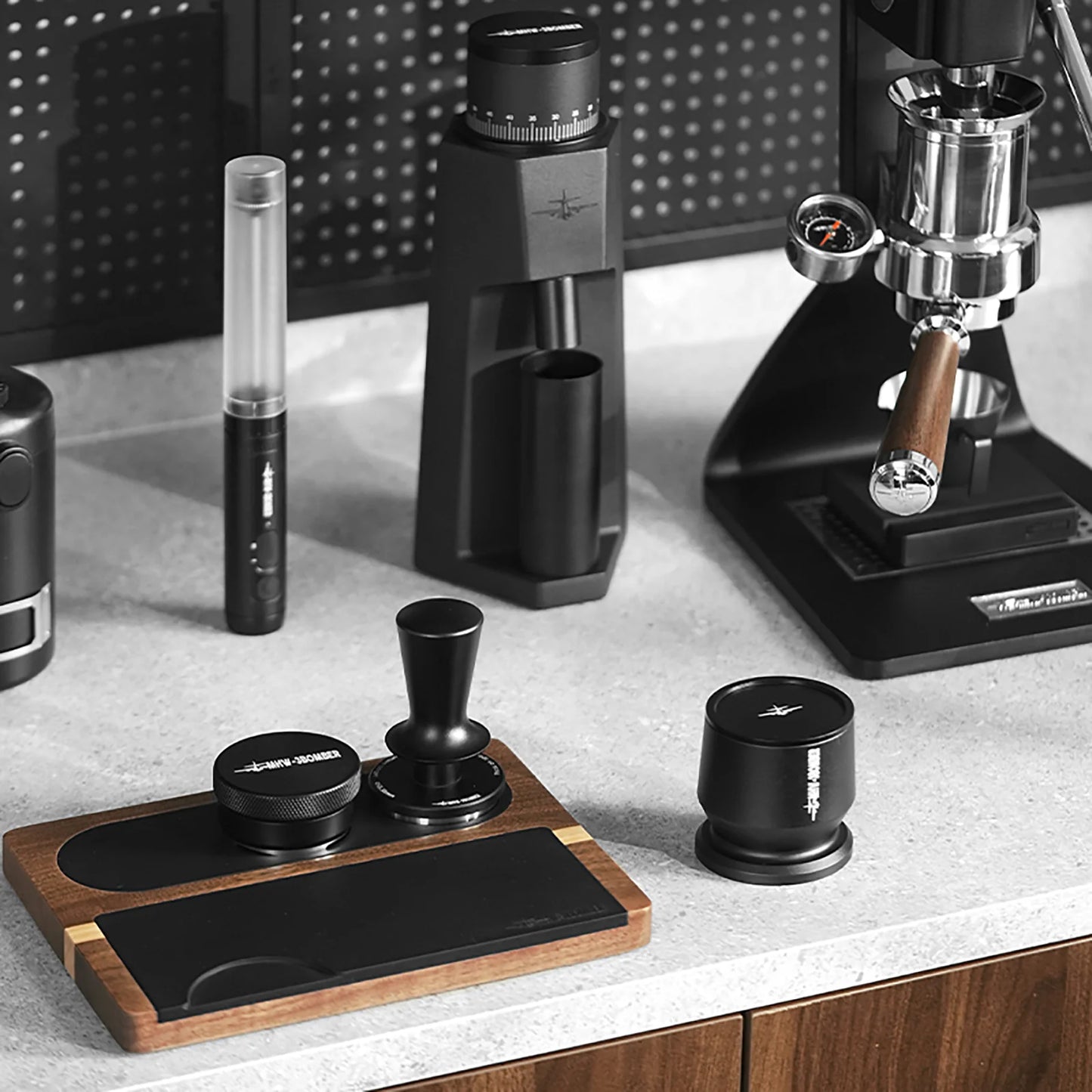 MHW-3BOMBER coffee tamper and accessories on a counter. Featuring a dual spring. Black and Wood.