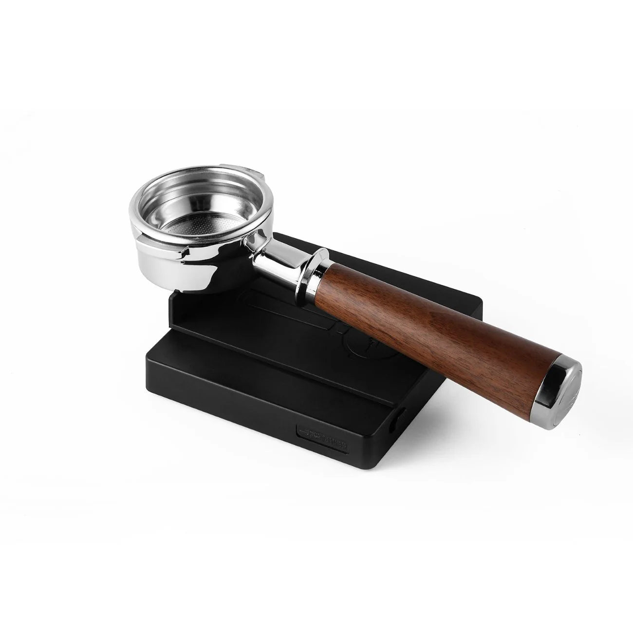 A sleek metal portafilter with a wooden handle rests on a black mat featuring subtle grooves, alongside the MHW-3BOMBER Espresso Scale Cube Coffee Scale 2.0, showing its modern design and precision.