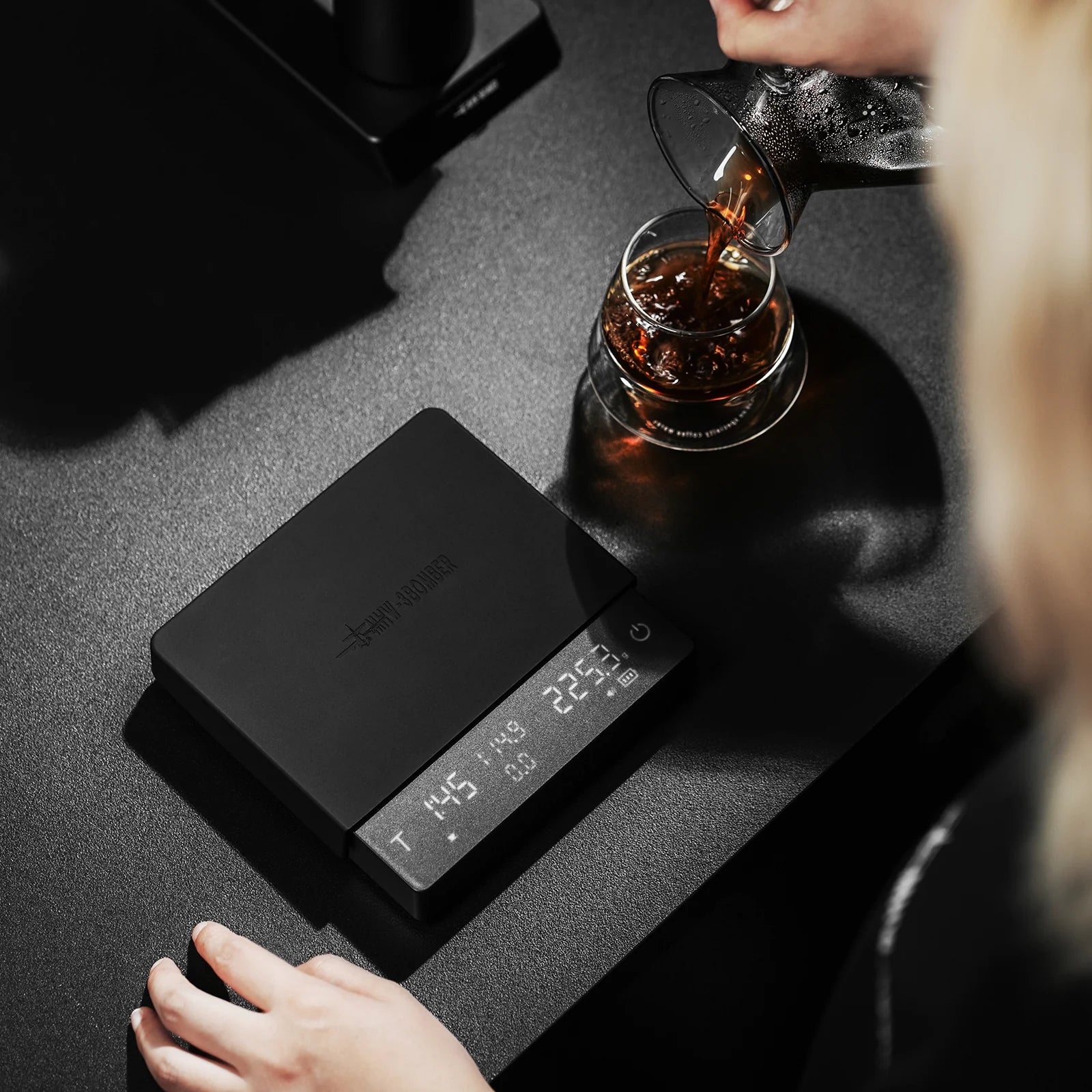MHW-3BOMBER black Cube Coffee Scale 3.0 Pro Max pouring coffee. Precise, modern design.