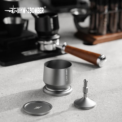 The MHW-3BOMBER Espresso Coffee Powder Dosing Funnel, with its silver finish and adjustable distributor handle, sits on the countertop. In the background, a coffee machine and wooden-handled tamper blur into view—essential tools for baristas honing their craft.