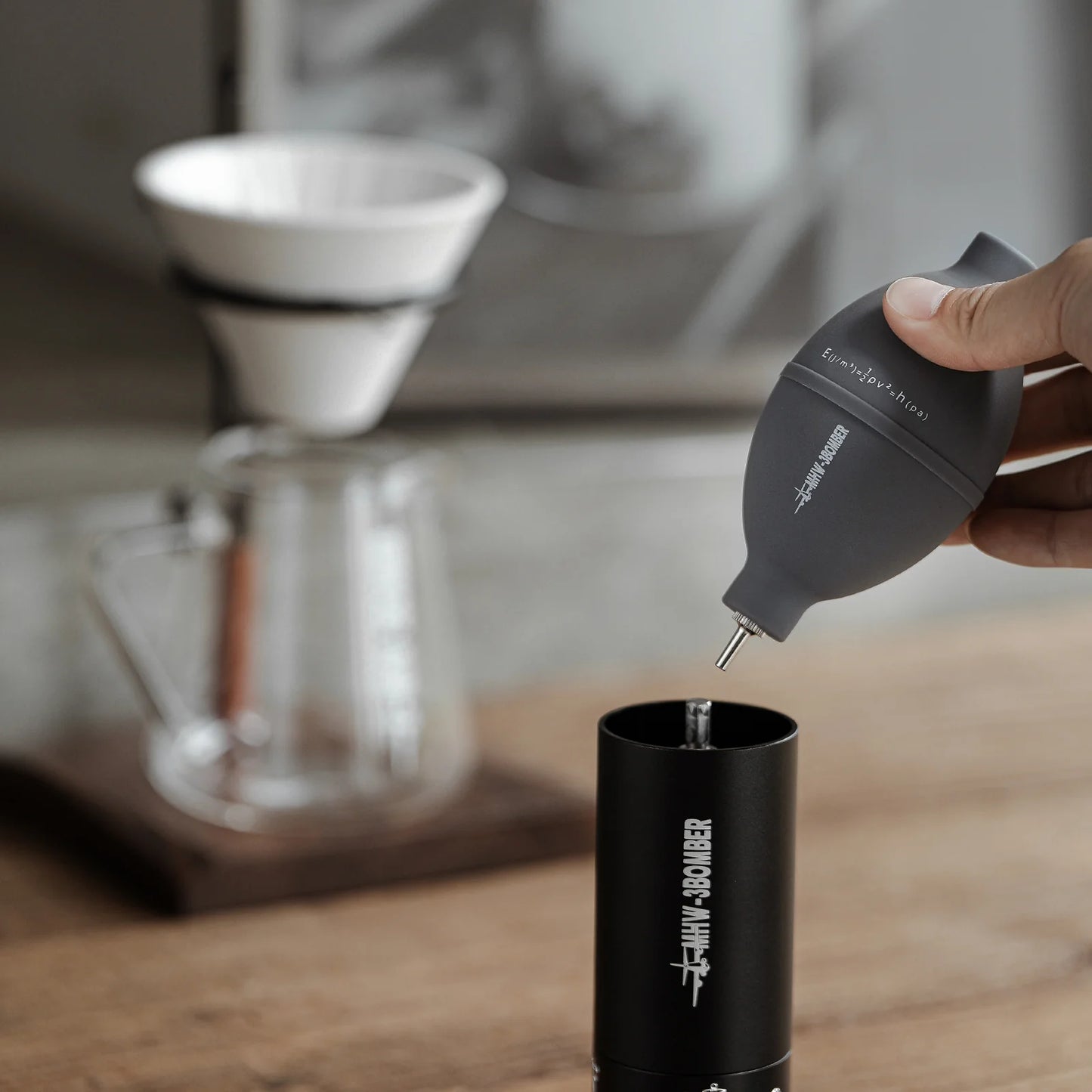 MHW-3BOMBER gray Coffee Air Blower being used to clean a grinder on a wooden surface.