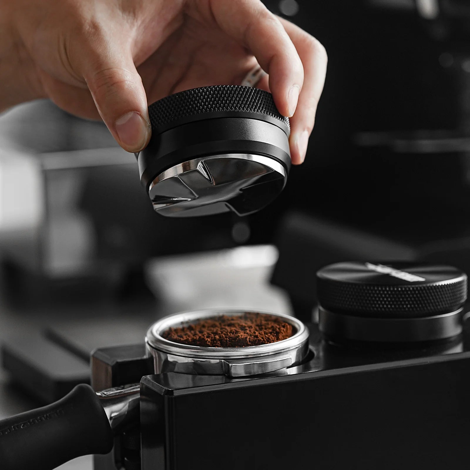 MHW-3BOMBER coffee distributor being used. Black & steel, adjustable height. Professional espresso tool.