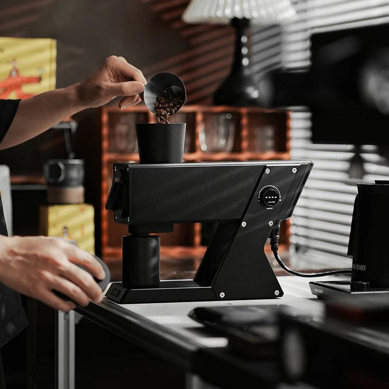 MHW-3BOMBER F74 Navigator black electric coffee grinder being used. Beans are being poured in.