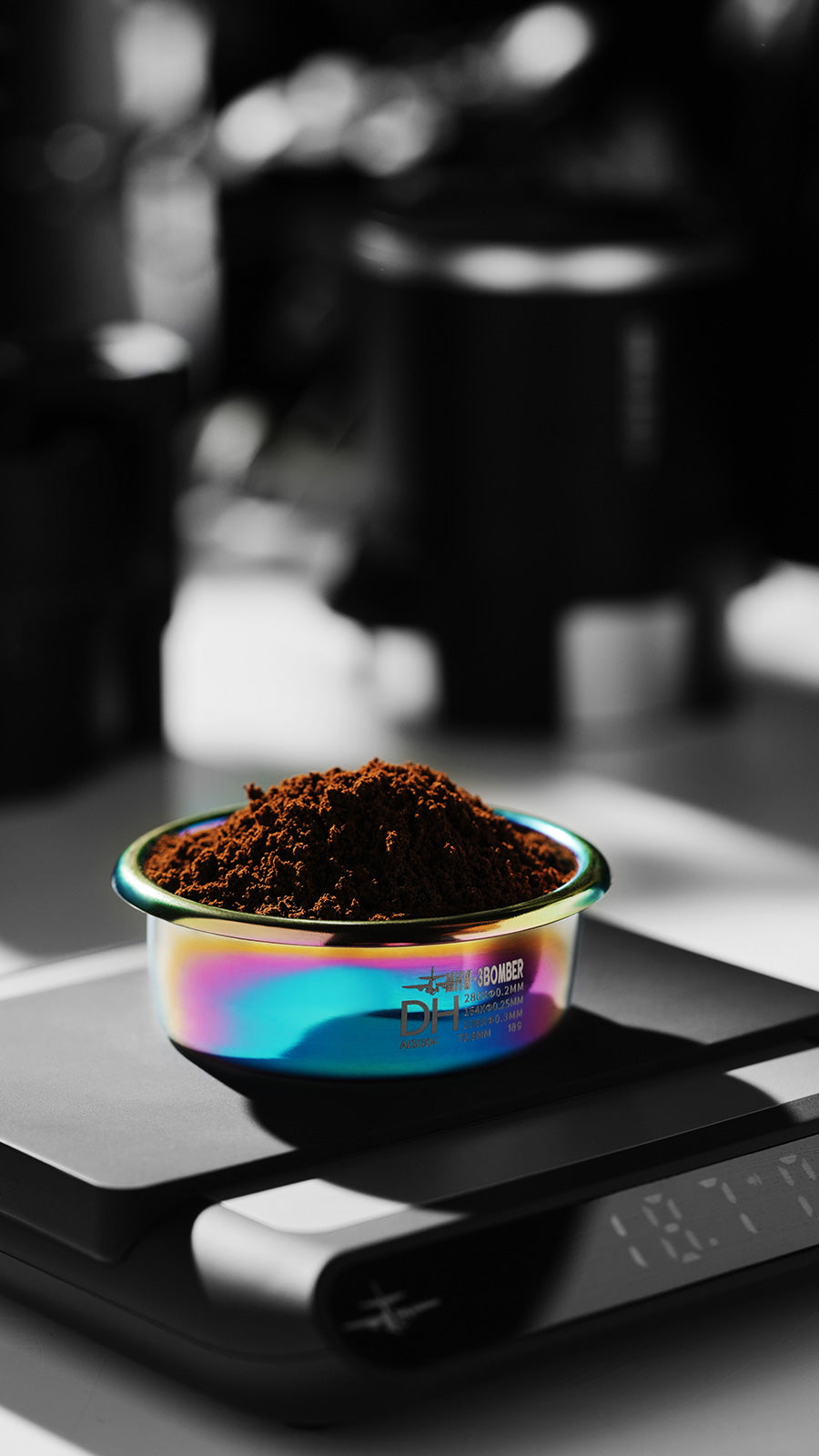 MHW-3BOMBER DH filter basket, 58mm, with coffee grounds, on scale. Iridescent finish.