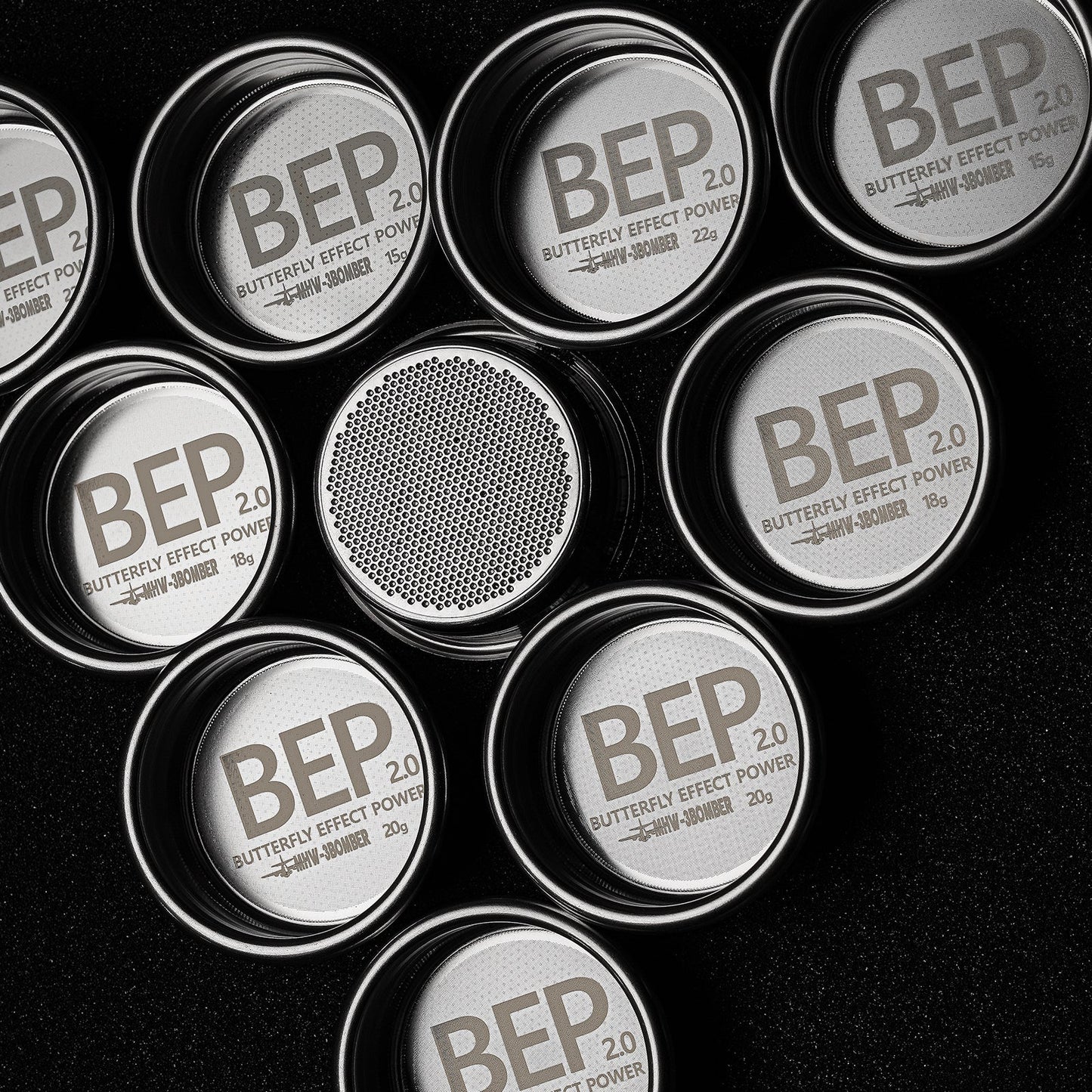 Circular stainless steel containers labeled MHW-3BOMBER BEP Butterfly Coffee Filter Basket 2.0 stand out against a black background. Some are open, revealing dual-layer filtration with fine mesh, reminiscent of an espresso filter basket. Sizes and weights differ slightly, marked in grams.