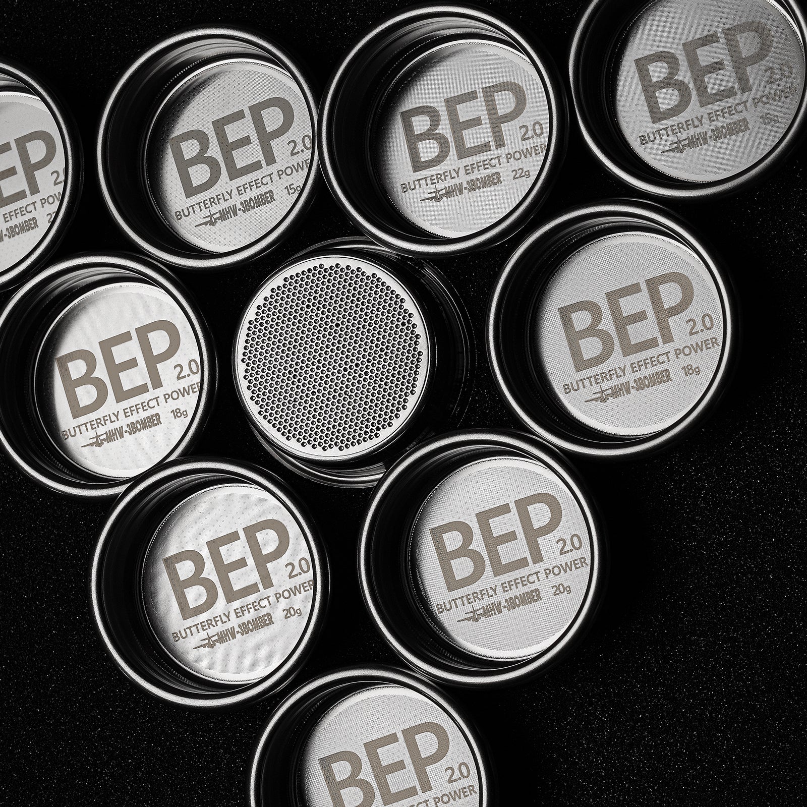 Circular stainless steel containers labeled MHW-3BOMBER BEP Butterfly Coffee Filter Basket 2.0 stand out against a black background. Some are open, revealing dual-layer filtration with fine mesh, reminiscent of an espresso filter basket. Sizes and weights differ slightly, marked in grams.