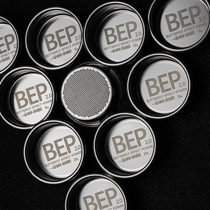 Circular stainless steel containers labeled MHW-3BOMBER BEP Butterfly Coffee Filter Basket 2.0 stand out against a black background. Some are open, revealing dual-layer filtration with fine mesh, reminiscent of an espresso filter basket. Sizes and weights differ slightly, marked in grams.