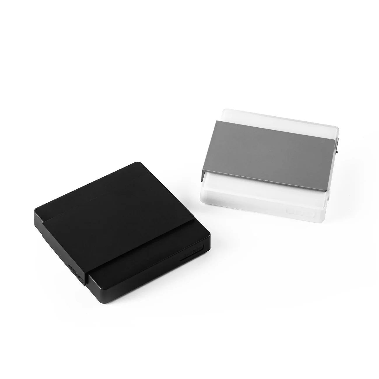 Two MHW-3BOMBER Espresso Scale Cube Coffee Scale 2.0 holders are shown: one black and closed, the other is transparent with a gray cover, partially open to reveal cards inside, on a plain white background.