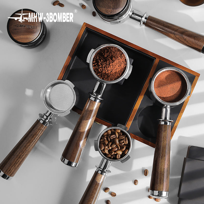 The top view highlights MHW-3BOMBER Bottomless Portafilters with natural walnut handles on a gray surface—one filled with ground coffee, one with beans, and another empty. Shadows pattern beside the stainless steel portafilters. The MHW-3BOMBER logo is at the top left corner.