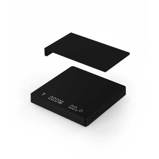 The MHW-3BOMBER Espresso Scale Cube Coffee Scale 2.0 is a sleek, black scale featuring an angled LCD for precise measurements, touch-sensitive buttons, USB rechargeability, and a matching lid against a plain white background.