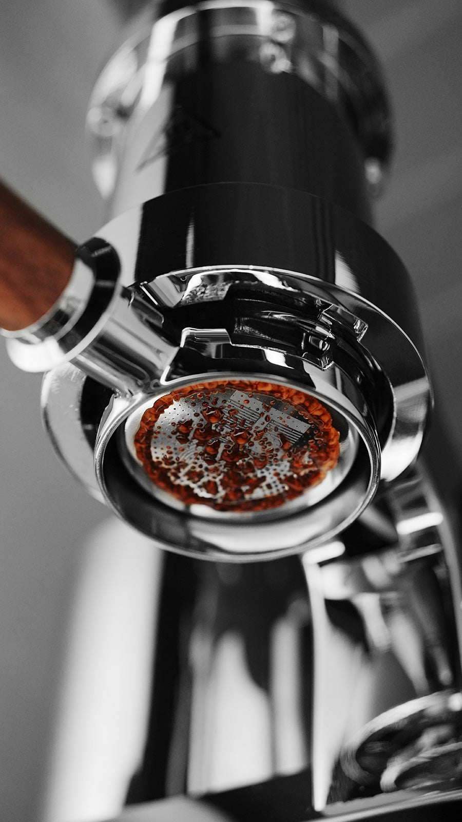 MHW-3BOMBER 58mm DH filter basket for espresso machine. Chrome finish with coffee grounds visible. 