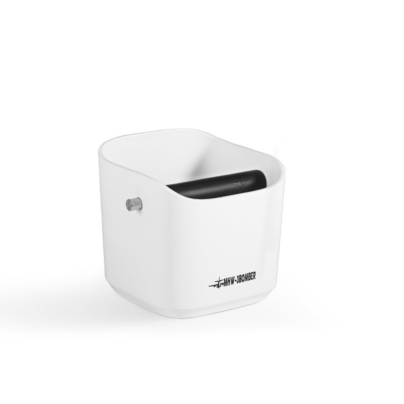 The MHW-3BOMBER Coffee Espresso Square Knock Box is white with a cylindrical top opening and black roller. Featuring a small metal pin on the side, it boasts the label WMW-SS0AMER on a durable surface set against a pristine white background. Ideal for coffee use.