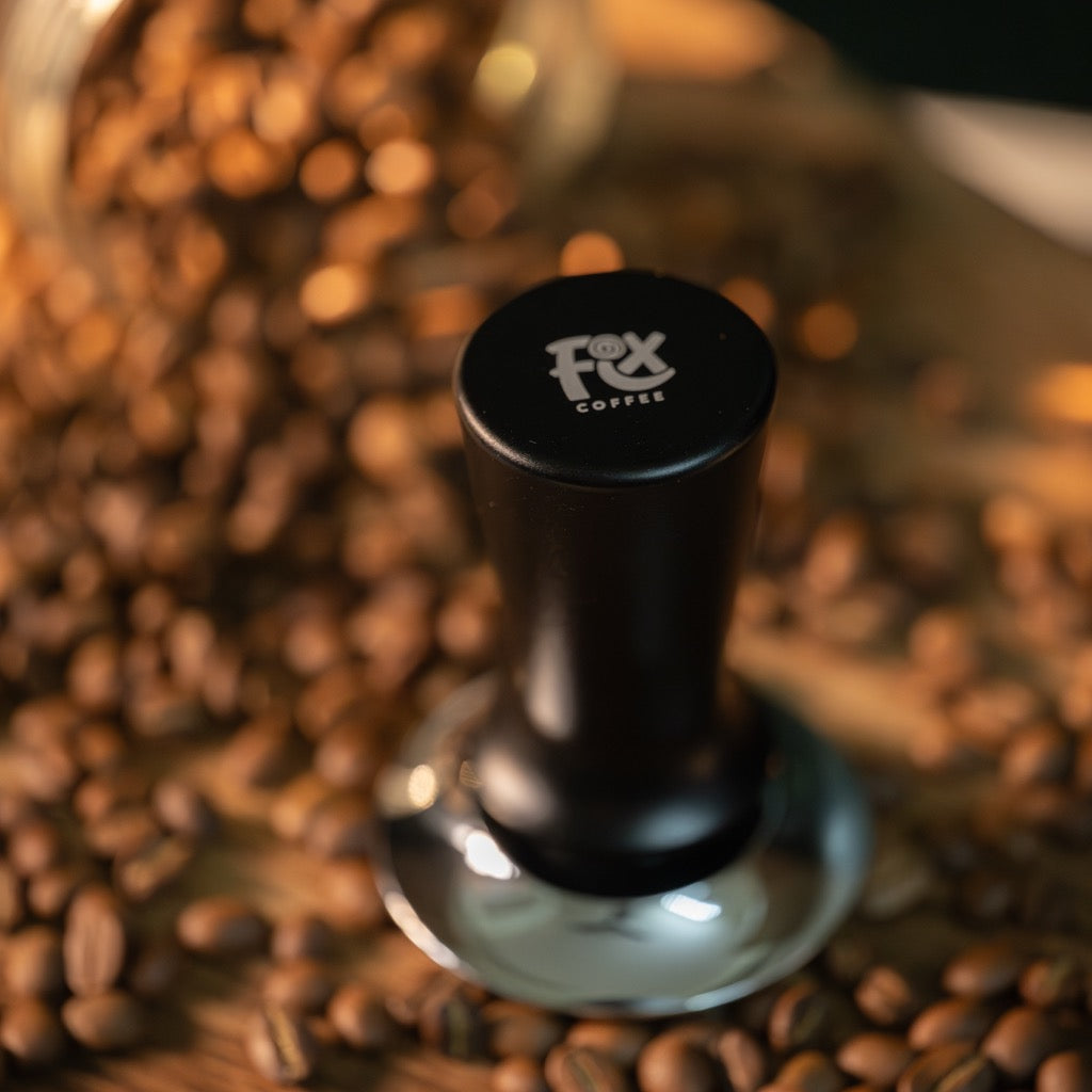 FIX COFFEE tamper on beans. Black, constant force, spring-activated level.