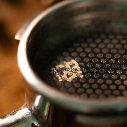 Close-up of a FIX COFFEE titanium plated espresso puck screen, showing its fine mesh and circular pattern.