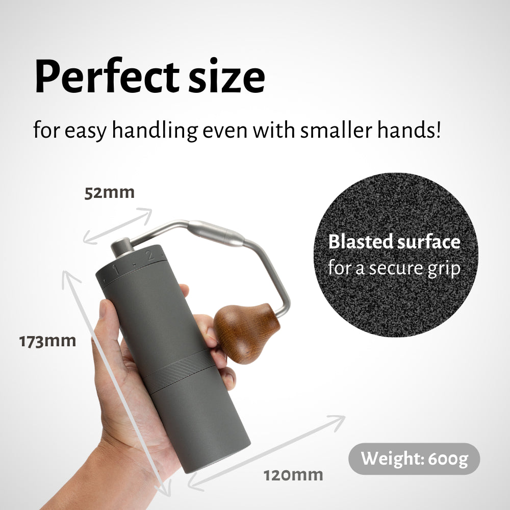 1Zpresso X-Ultra gray manual coffee grinder with wooden handle, shown held in hand. Compact size, blasted texture for grip.