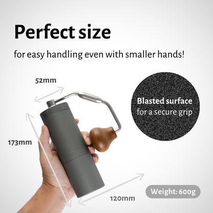 1Zpresso X-Ultra gray manual coffee grinder with wooden handle, shown held in hand. Compact size, blasted texture for grip.