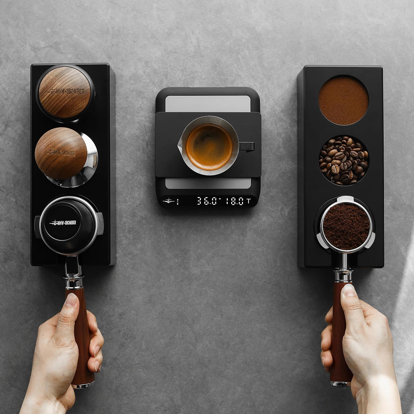MHW-3BOMBER black ABS tamper station with portafilter and scale on a gray wall. Coffee accessories.