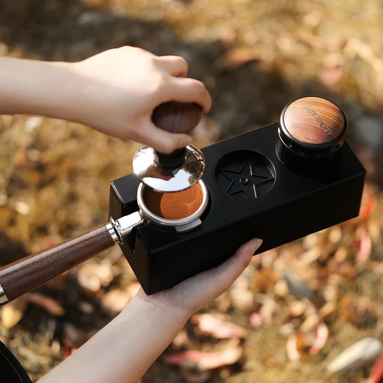 MHW-3BOMBER black ABS portafilter holder being used with tamper and portafilter. 