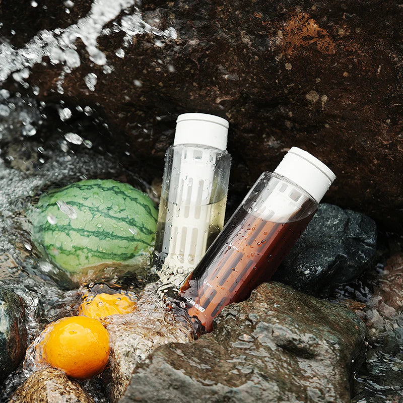 MHW-3BOMBER cold brew maker, 600ml, clear Tritan bottle with white cap, filter inside, outdoors with fruit.