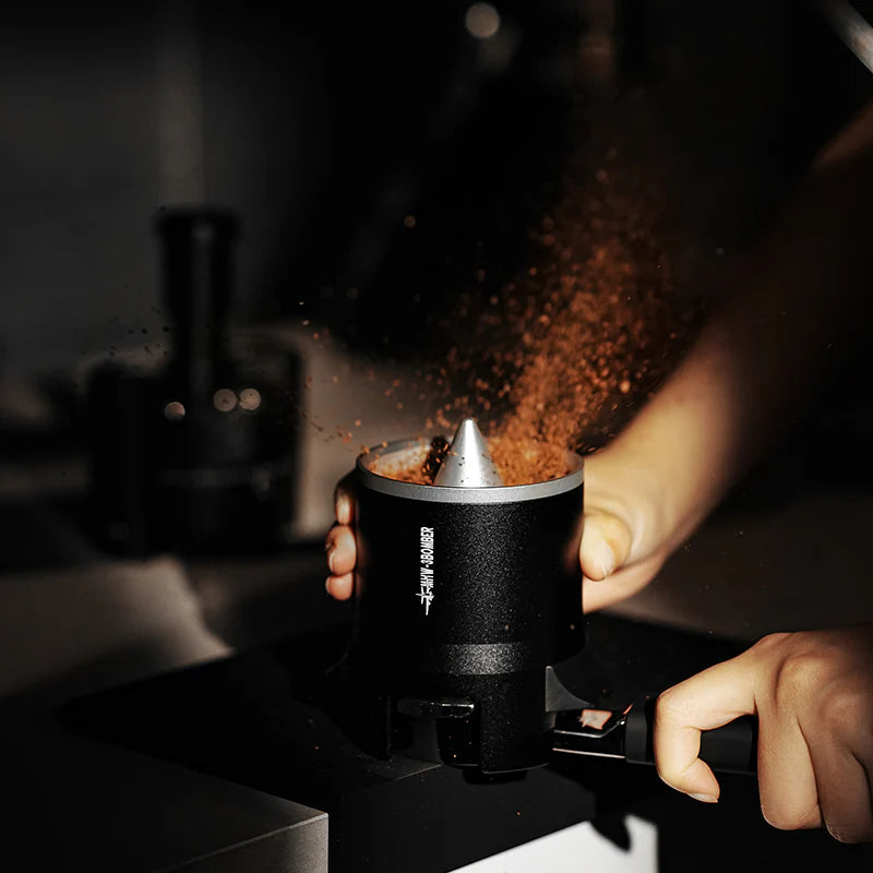 MHW-3BOMBER SE Pro black espresso shaker funnel in use, distributing coffee grounds. 
