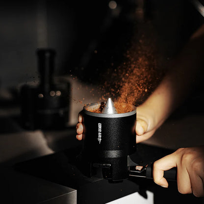 MHW-3BOMBER SE Pro black espresso shaker funnel in use, distributing coffee grounds. 