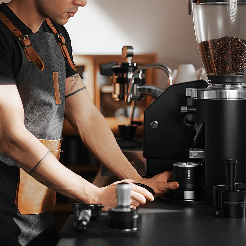 MHW-3BOMBER SE Pro espresso shaker funnel in use. Black cylindrical design for even grounds distribution.