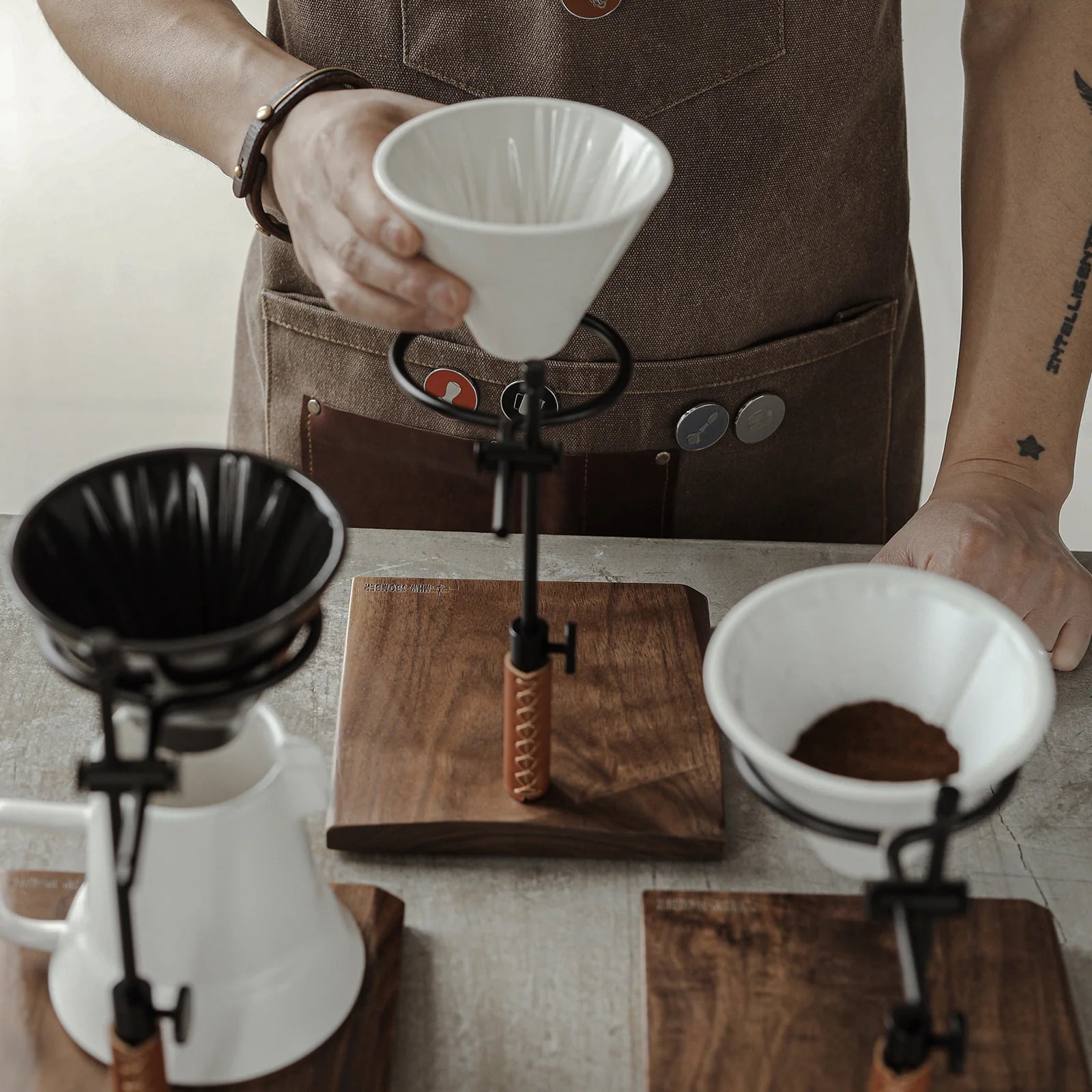 MHW-3BOMBER adjustable coffee dripper stand with white ceramic dripper on wooden base, in use. 
