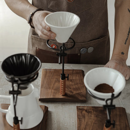 MHW-3BOMBER adjustable coffee dripper stand with white ceramic dripper on wooden base, in use. 